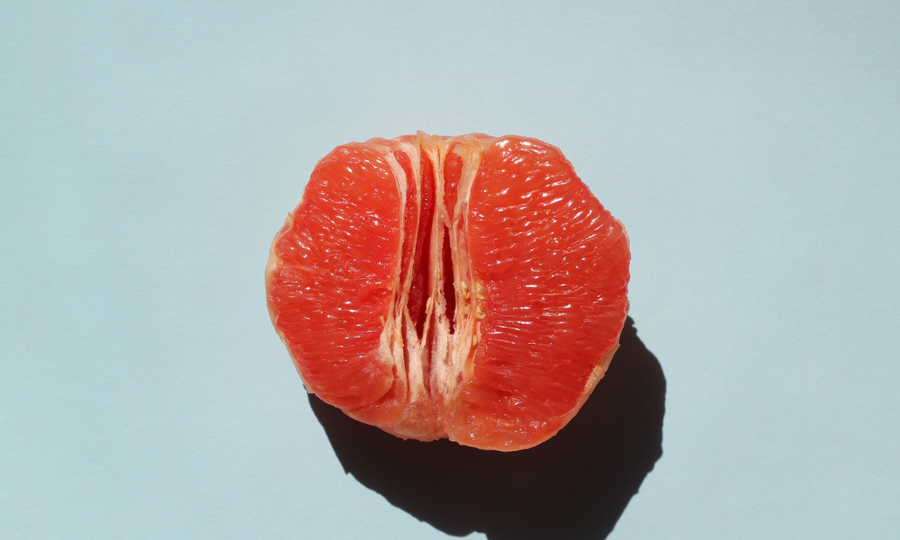 Pomelo rojo partido sobre fondo azul claro