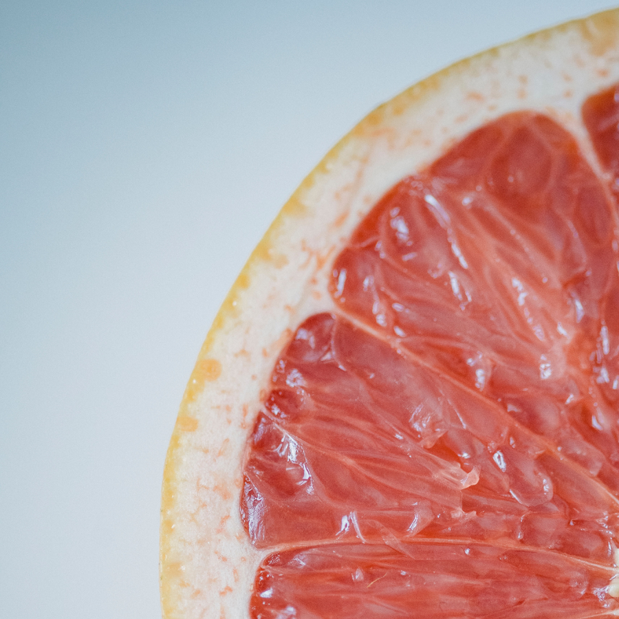 Medio pomelo rojo sobre fondo azul claro