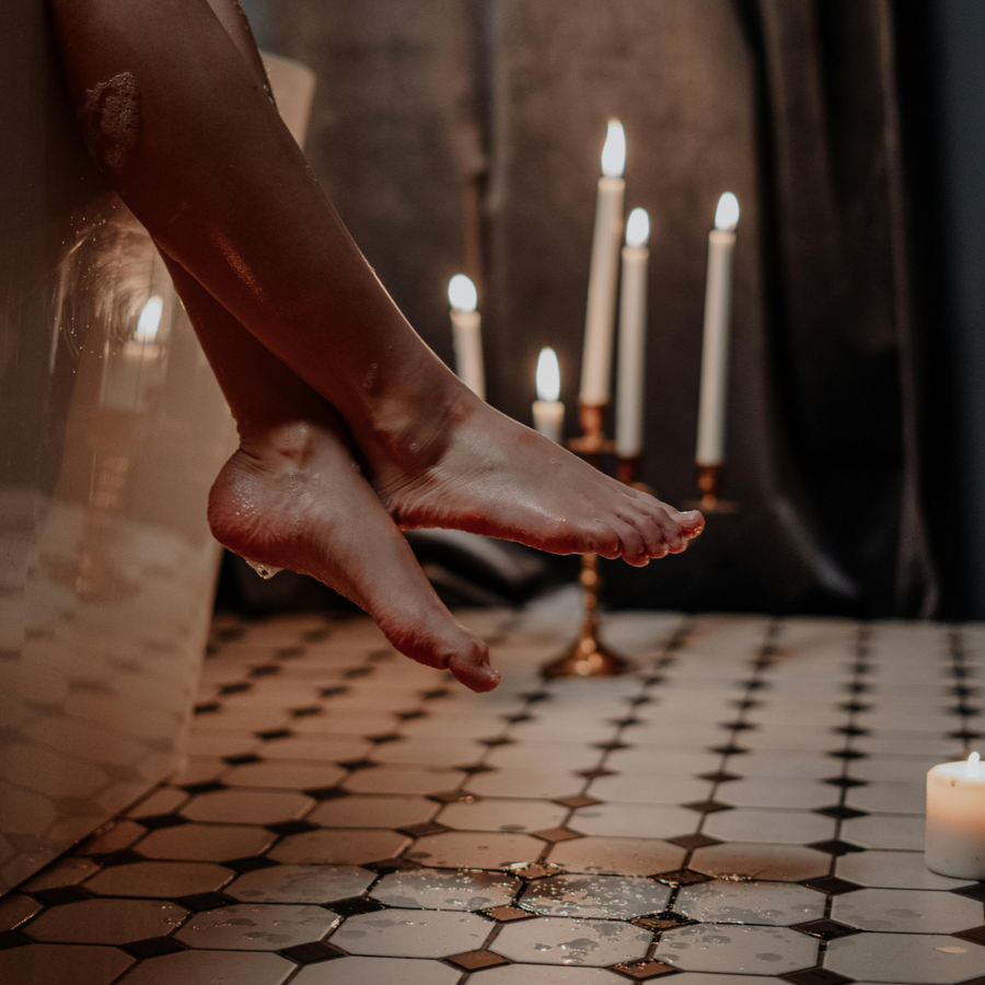 Piernas de mujer saliendo de una bañera junto a velas encendidas