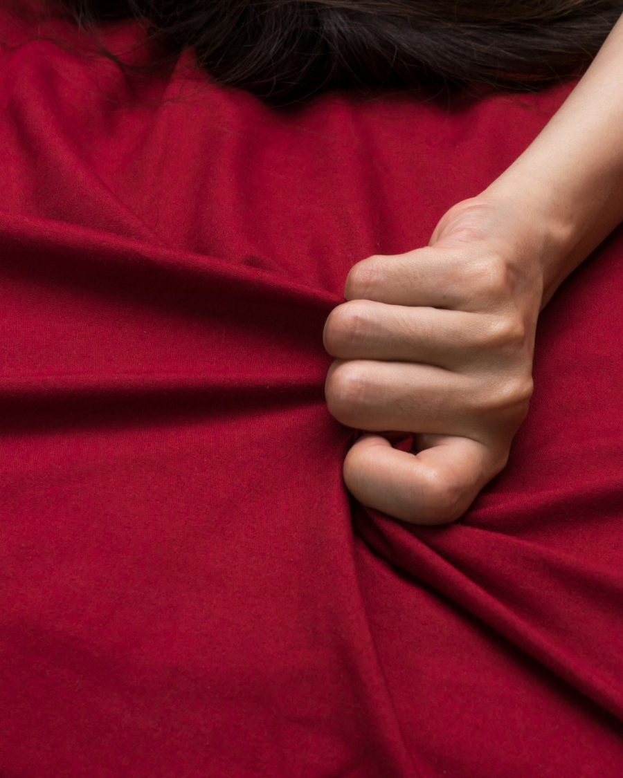 Mano apretando una sábana roja