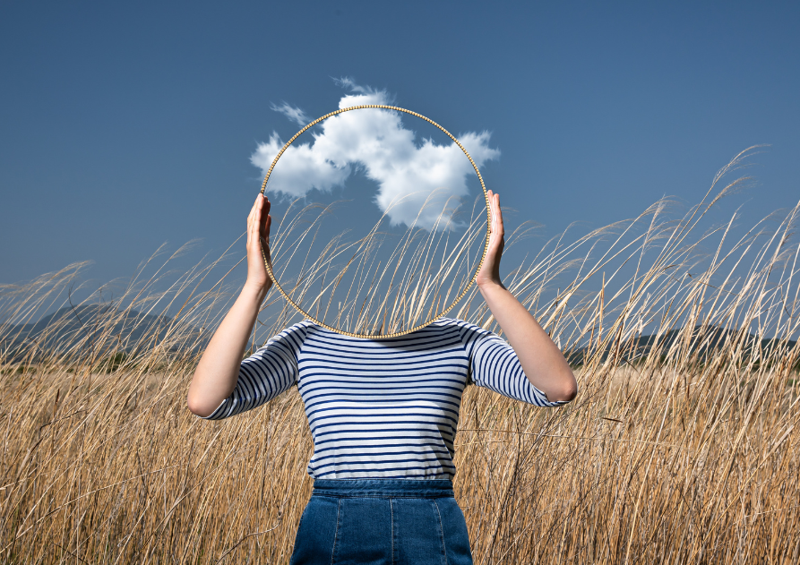 Mujer en un campo con una nube tapándole la cabeza