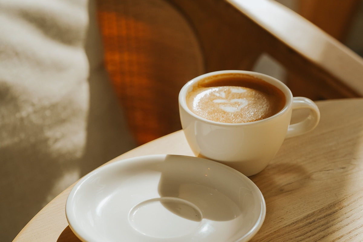 Una taza de café sobre una mesa de madera y, al lado, un plato vacío