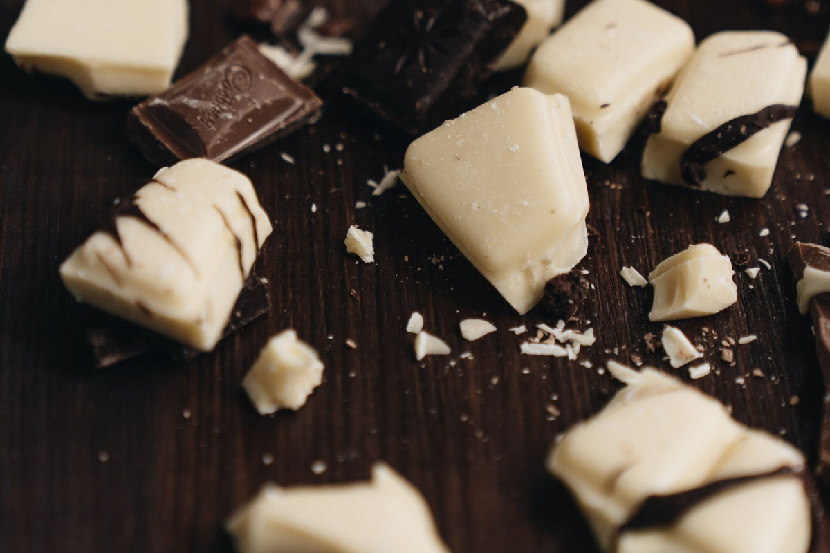 Trozos de chocolate negro y blanco esparcidos sobre una mesa de madera