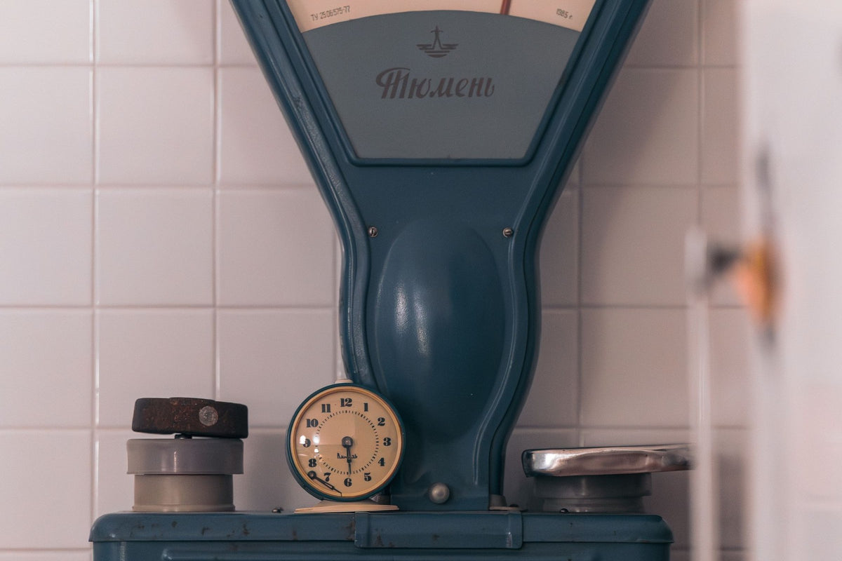 Una báscula de cocina antigua sobre una encimera, junto a unos botes