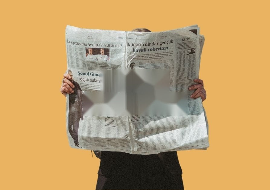 Una persona leyendo un periódico desplegado, sobre fondo naranja