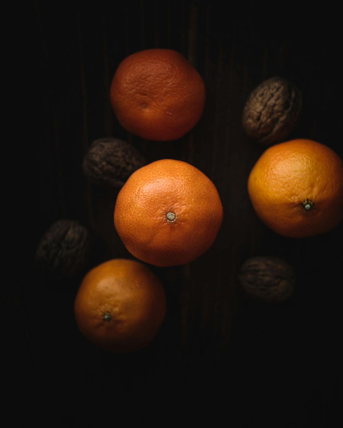 Naranjas y nueces sobre una mesa de madera oscura