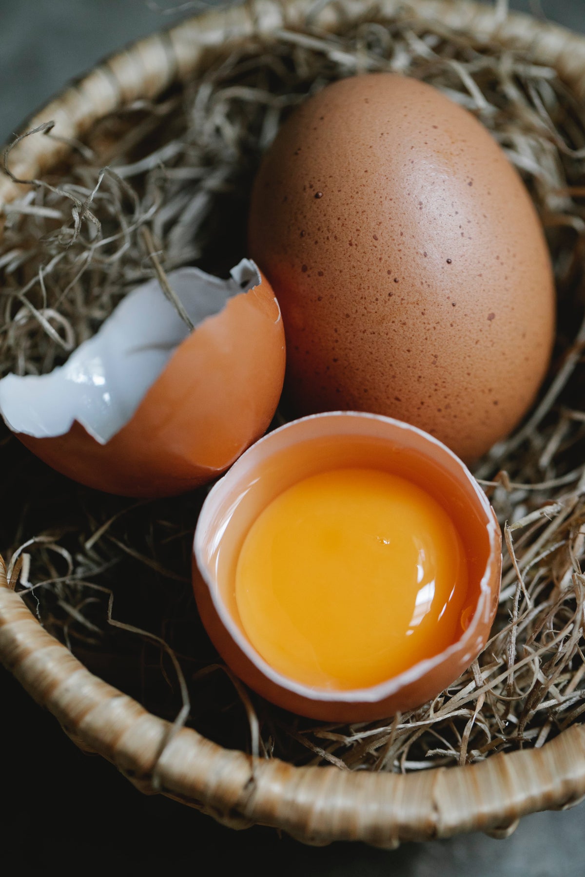 Huevos en un nido de paja, uno abierto con la yema