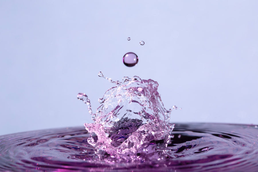 Gota de agua cayendo sobre una superficie lila