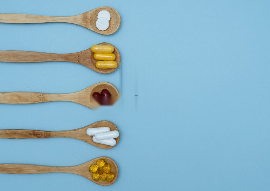 Cucharas de madera con distintos suplementos sobre fondo azul